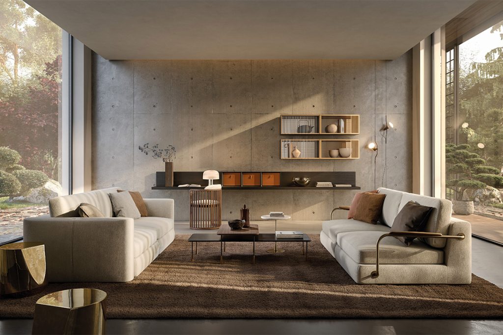Modern living room with two white sectional sofas facing each other, a brown rug, and a concrete accent wall with open shelving.