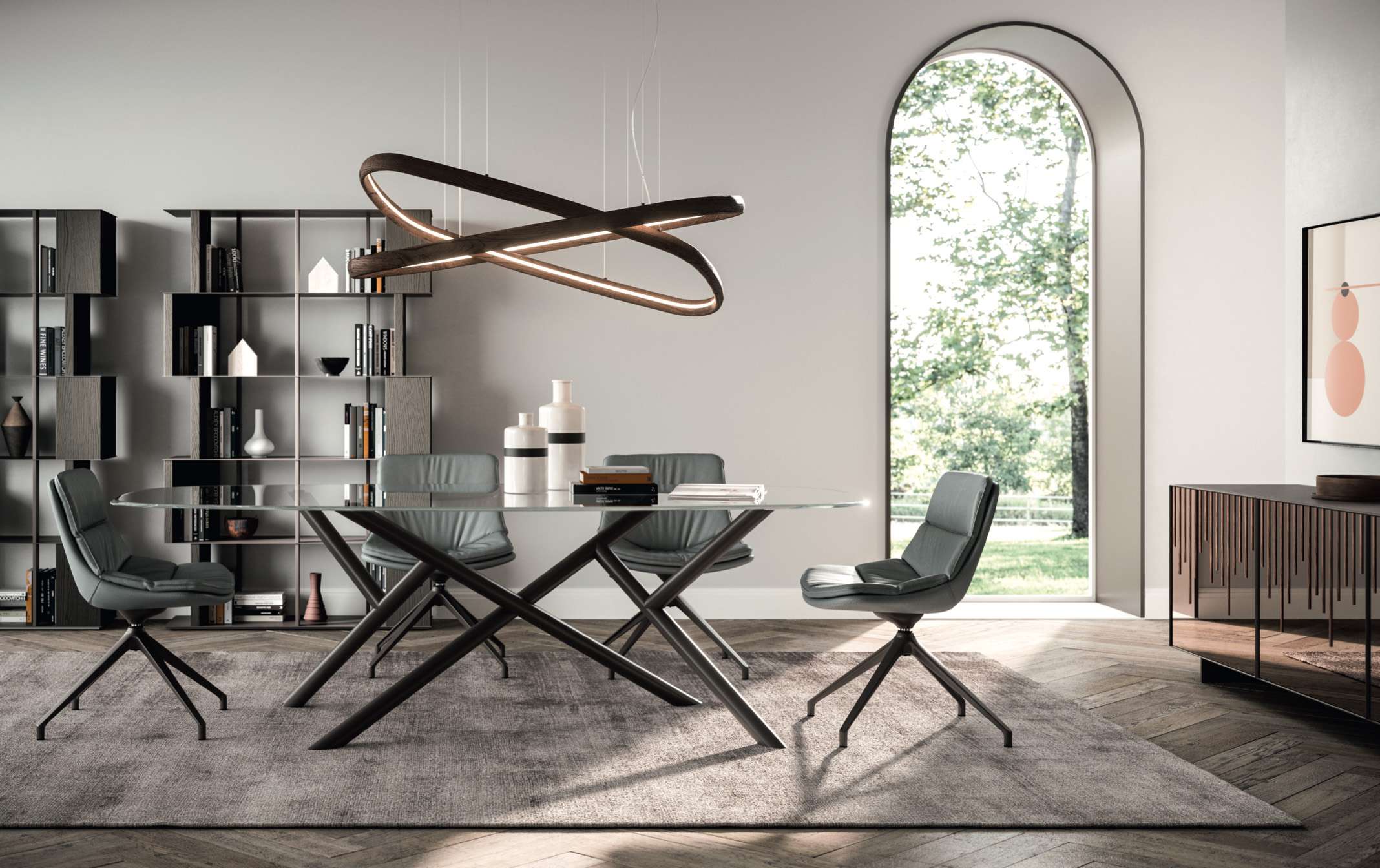 Modern dining room with a glass oval table, six gray chairs, a sculptural looping chandelier, and a tall arched window.