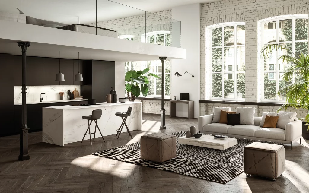 Open-plan loft living area with a marble kitchen island, mezzanine bedroom, black cabinets, pendant lights, and greenery by large windows.