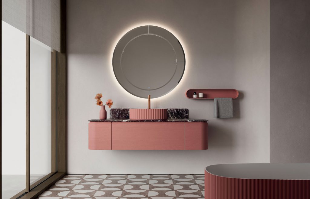 Modern bathroom with a large circular backlit mirror above a pink vanity and marble countertop.