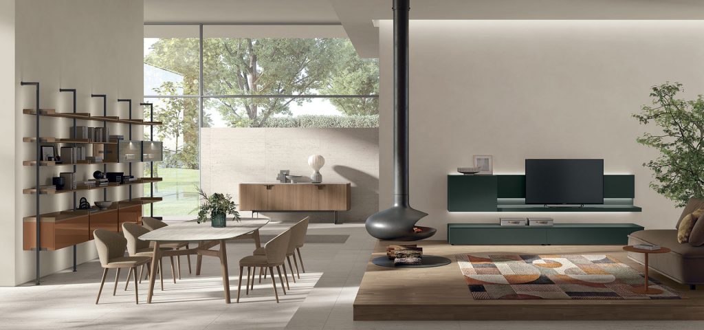 Open-plan living and dining area with a round dining table, six wooden chairs, and a tall open shelving unit along the left wall, large windows outside.